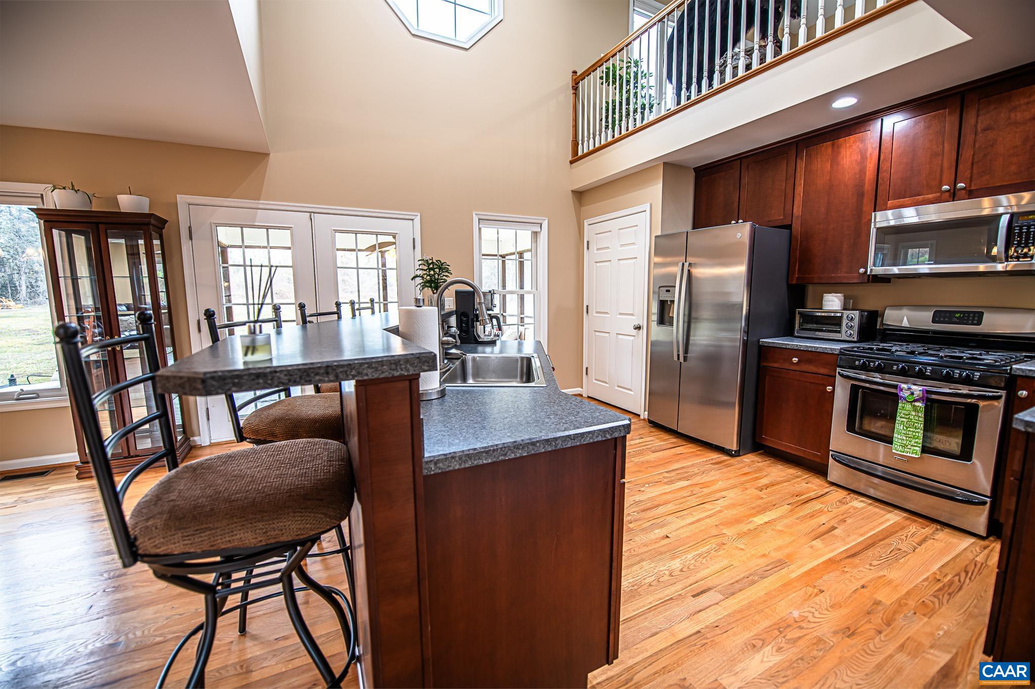 1101 Keith Road Stanardsville, VA 22973 - Photo 20 of 38 a kitchen with stainless steel appliances wooden floor dining table and chairs