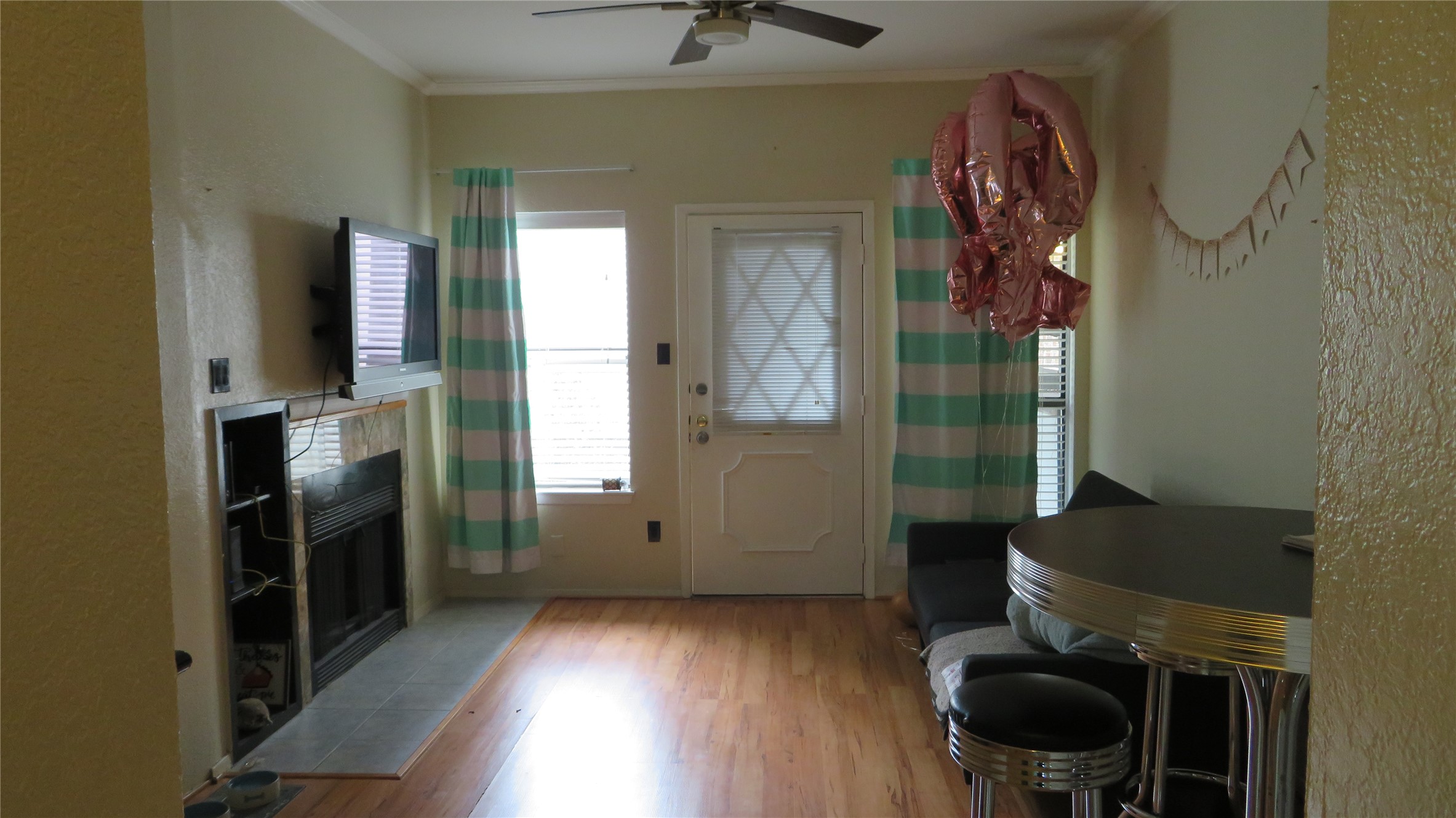 806 West 24th Street, Unit 200 Austin, TX 78705 - Photo 13 of 33 A cozy living space features hardwood flooring, a fireplace, and a ceiling fan for year-round comfort.
