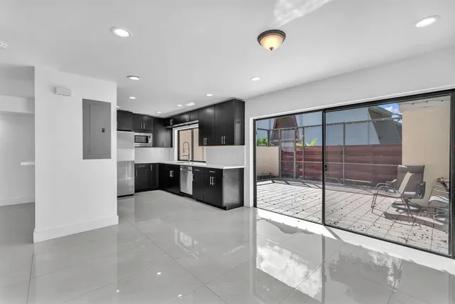 a large white kitchen with a sink and stainless steel appliances