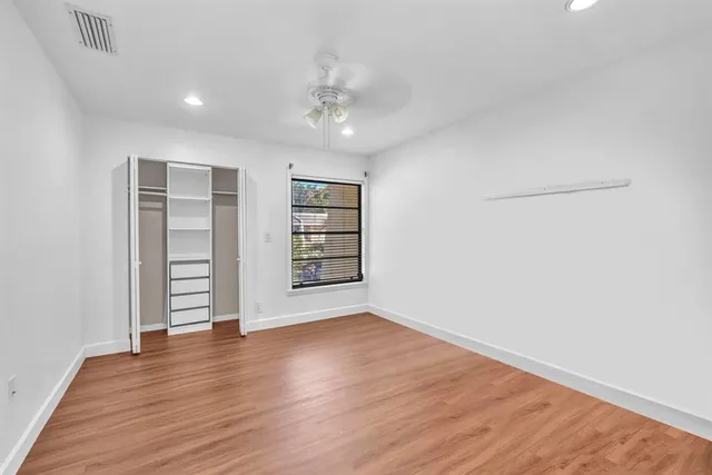 an empty room with wooden floor closet and windows