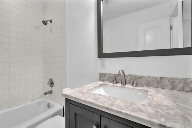 a bathroom with a granite countertop sink a mirror and bathtub