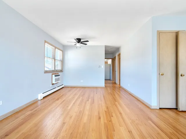 a view of empty room with wooden floor and fan