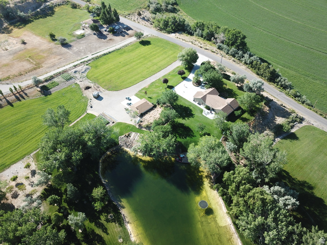 1040 West Mill Road Ferron, UT 84523 - Photo 1 of 117 Expansive property featuring a large body of water, extensive green lawns, mature trees, a private driveway, and a residential structure with a shingled roof