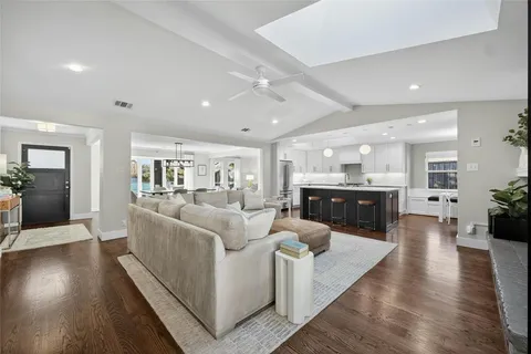 a living room with furniture kitchen view and a wooden floor