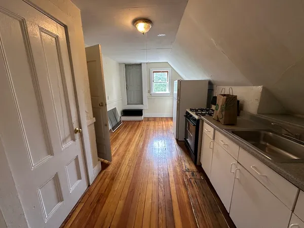 a kitchen with sink a refrigerator and wooden floor