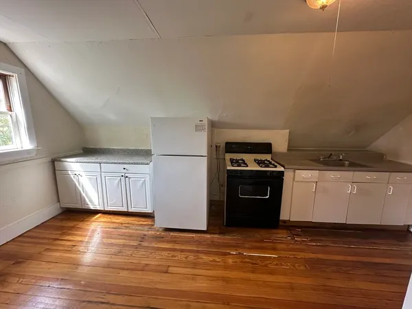a kitchen with a refrigerator stove and wooden floor