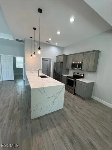 a large kitchen with stainless steel appliances a large counter top a sink a refrigerator and a fireplace