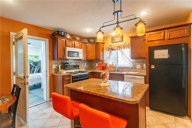 a kitchen with stainless steel appliances granite countertop a sink refrigerator and cabinets