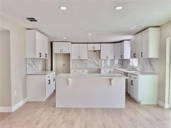 a kitchen with kitchen island a white cabinets and refrigerator