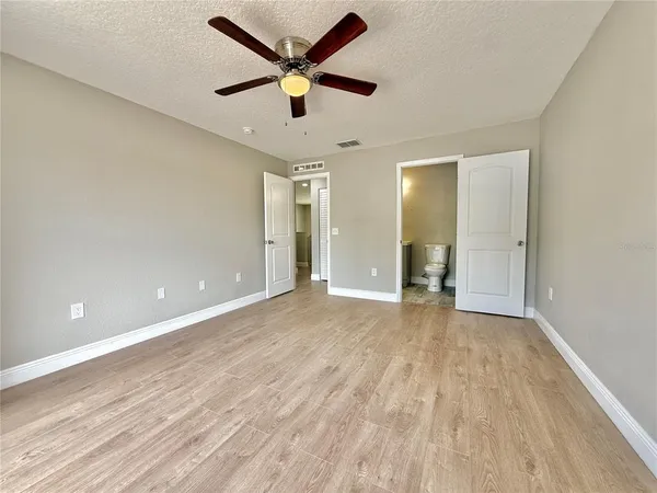 a view of a hallway with wooden floor and a bathroom