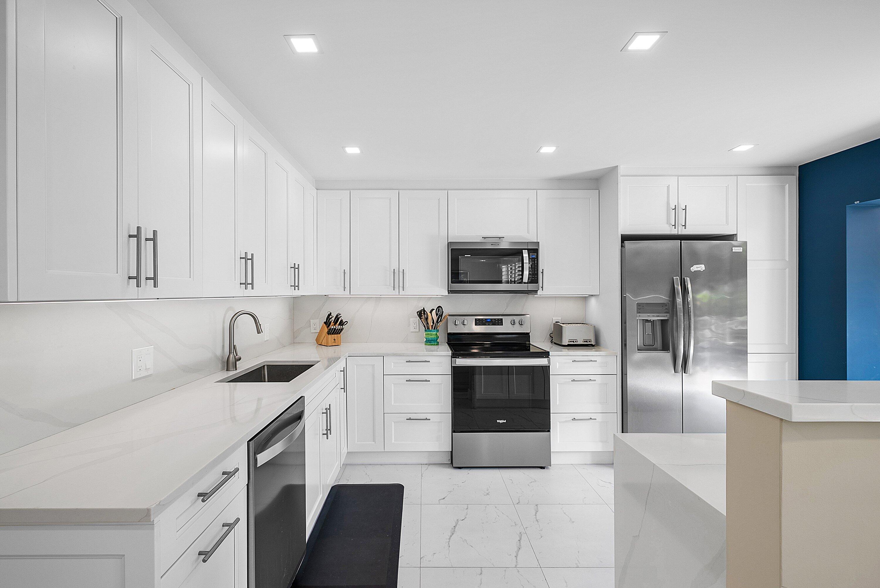 3709 North Quail Ridge Drive, Unit BOBWHITE B Boynton Beach, FL 33436 - Photo 11 of 51 a kitchen with granite countertop a refrigerator sink and white cabinets