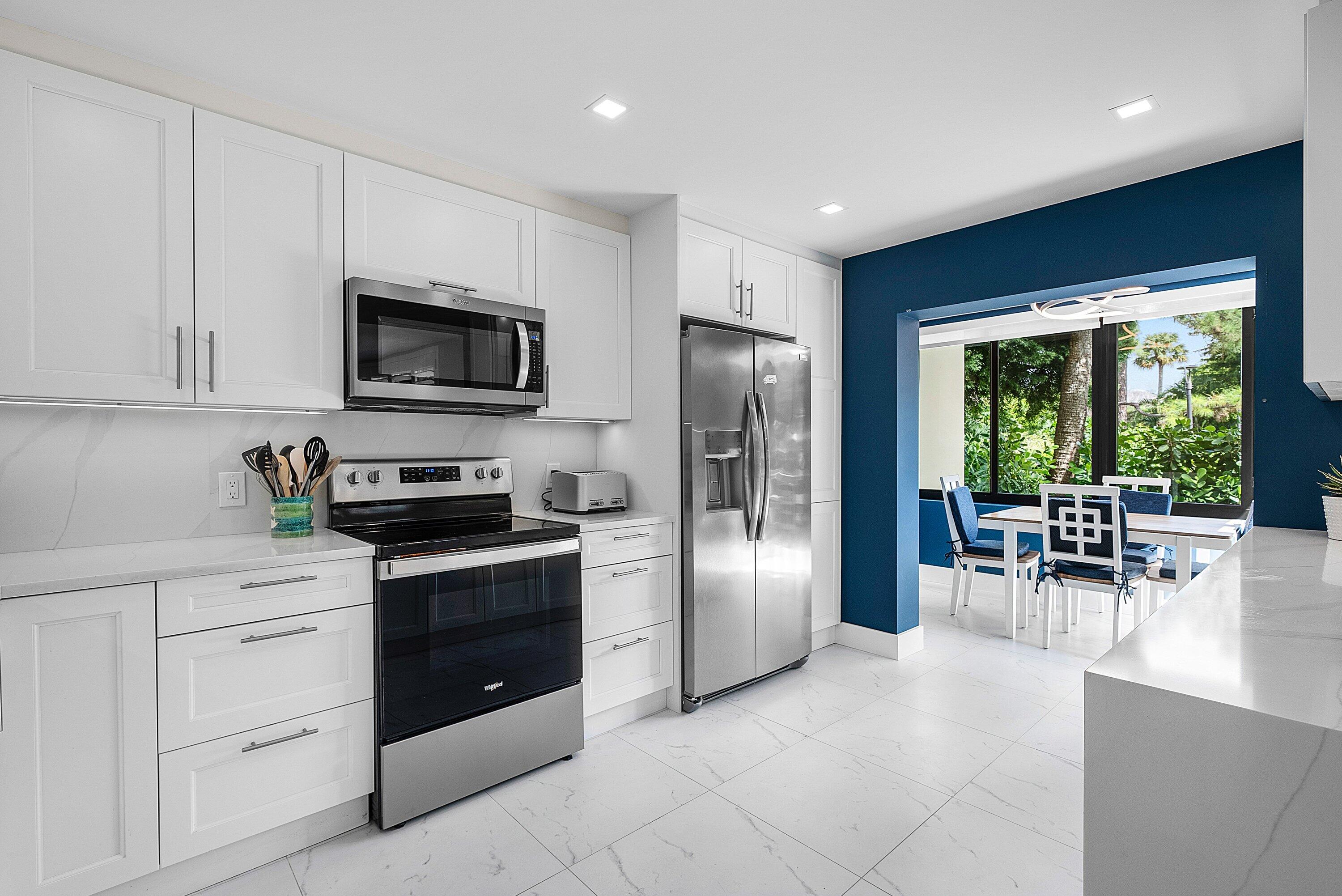 3709 North Quail Ridge Drive, Unit BOBWHITE B Boynton Beach, FL 33436 - Photo 15 of 51 a kitchen with stainless steel appliances granite countertop a stove a refrigerator a microwave a dining table and chairs with white cabinets