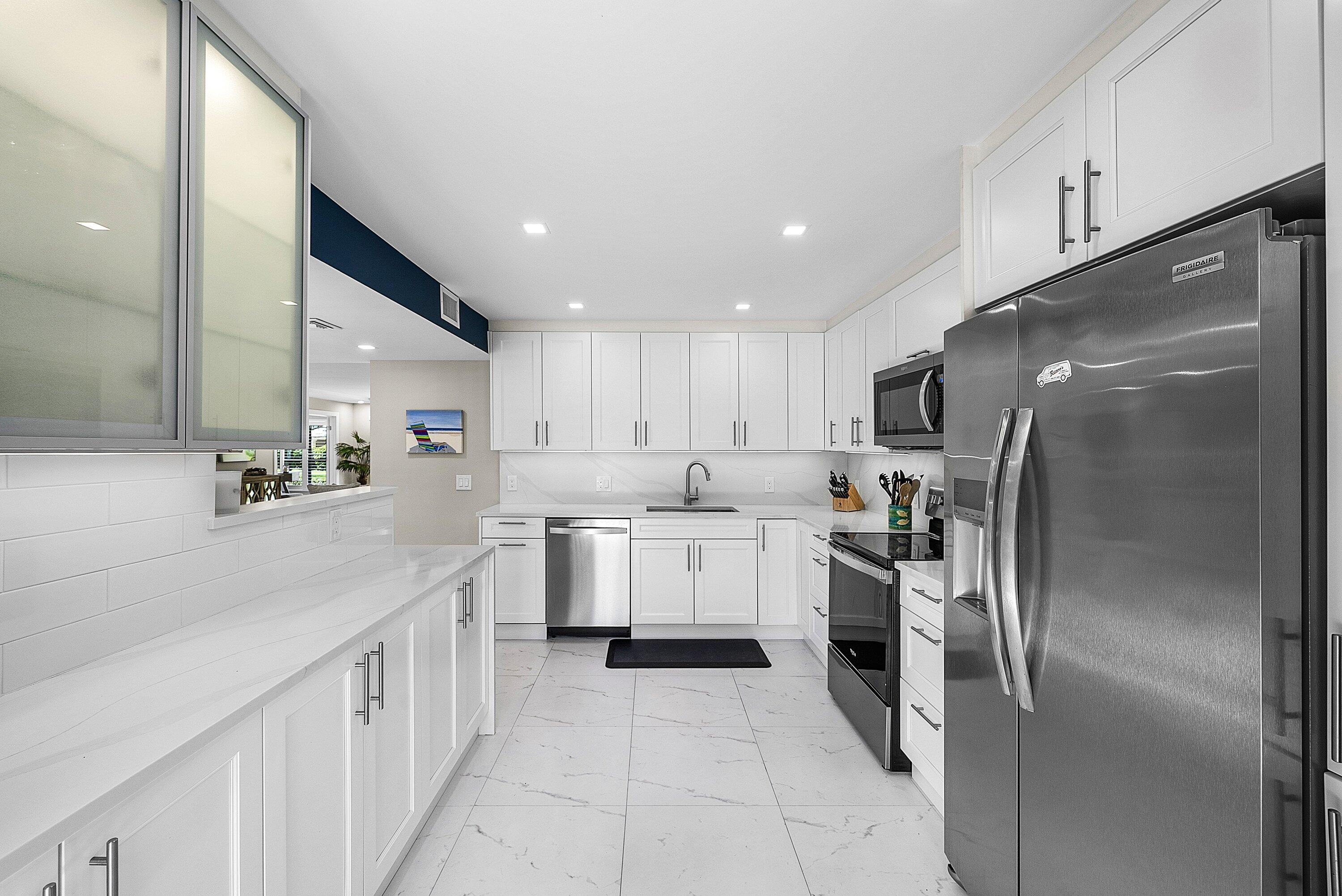 3709 North Quail Ridge Drive, Unit BOBWHITE B Boynton Beach, FL 33436 - Photo 3 of 51 a kitchen with stainless steel appliances kitchen island granite countertop a refrigerator and a sink