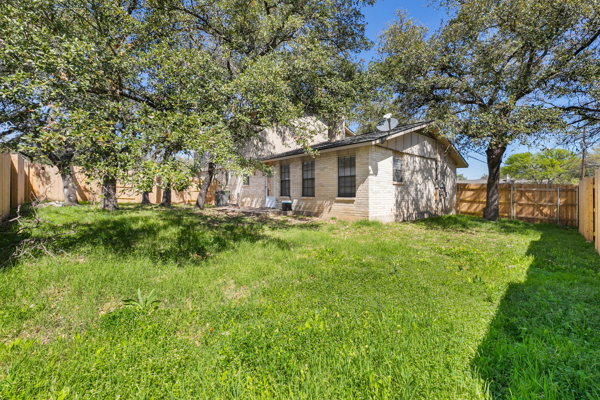 3802 Foust Trail, Unit A Georgetown, TX 78628 - Photo 32 of 34 A well-maintained yard provides ample space for recreation and enjoyment, framed by mature shade trees and a sturdy privacy fence.