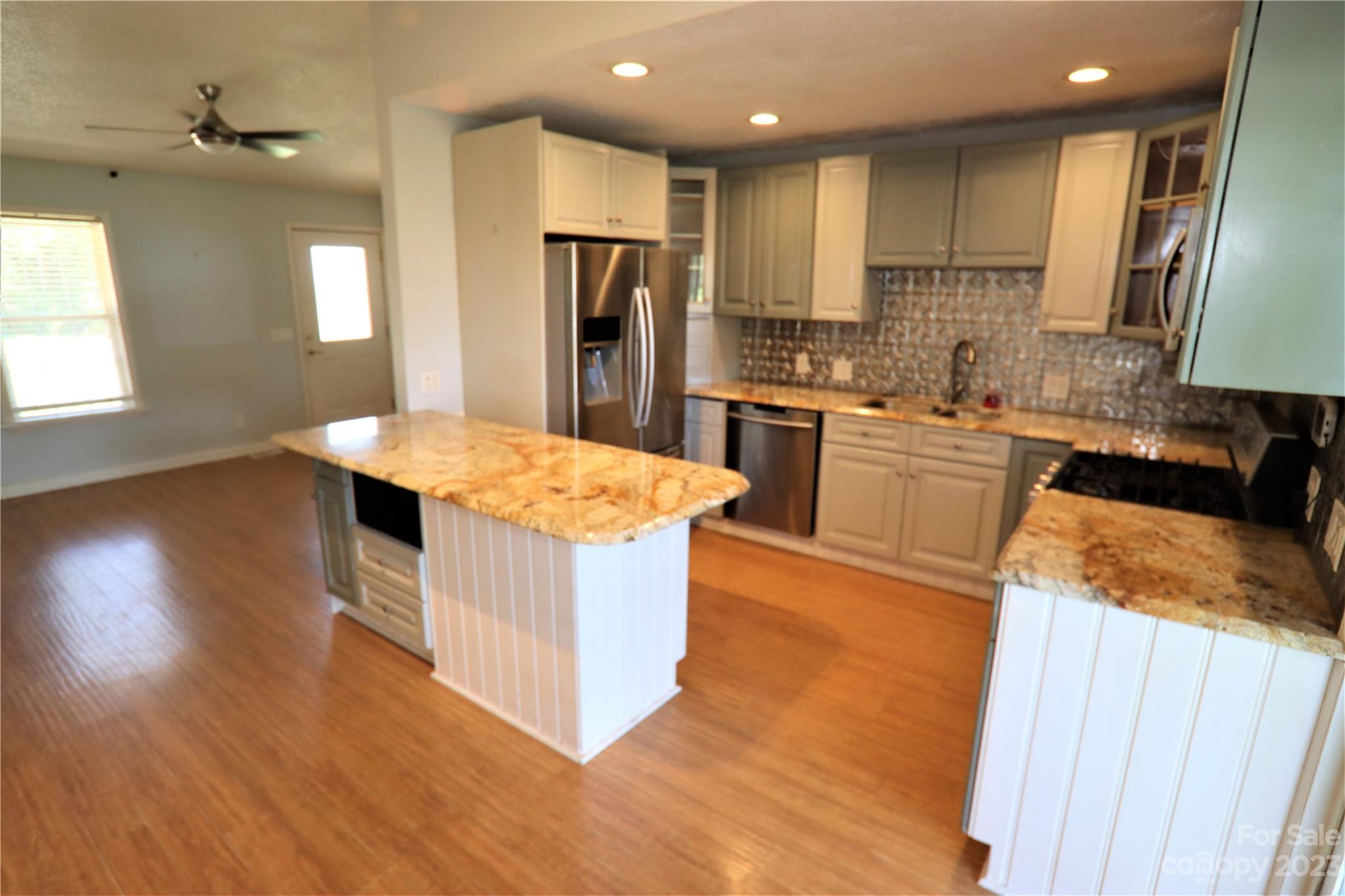 12725 Mooresville Road Mount Ulla, NC 28125 - Photo 4 of 23 a kitchen with stainless steel appliances granite countertop a refrigerator a sink dishwasher a stove and white countertops with wooden floor