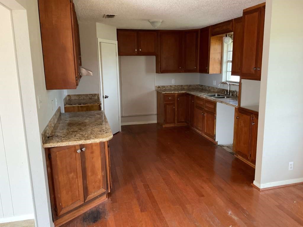 1501 Azalea Street Sweeny, TX 77480 - Photo 5 of 12 a kitchen with granite countertop wooden floors and stainless steel appliances