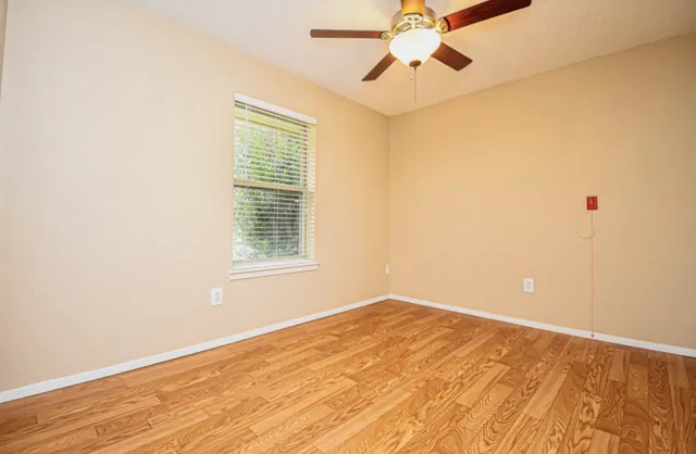 a view of empty room with wooden floor and fan