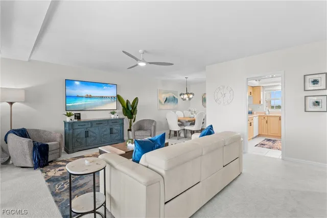 a living room with furniture a flat screen tv and kitchen view
