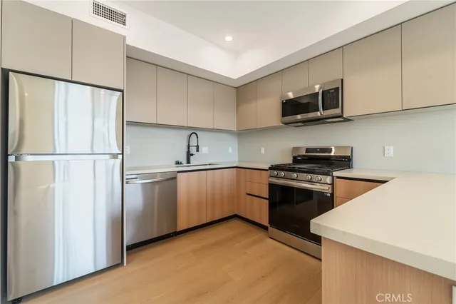 a kitchen with stainless steel appliances granite countertop white cabinets a sink a stove a refrigerator and a microwave