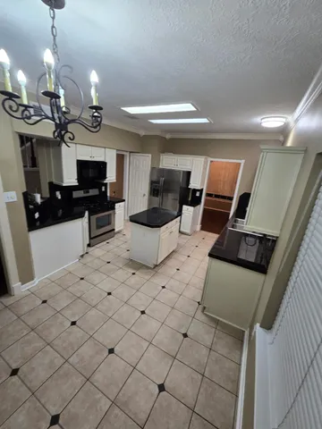 a kitchen with stainless steel appliances kitchen island granite countertop a sink dishwasher and a black countertop with white cabinet