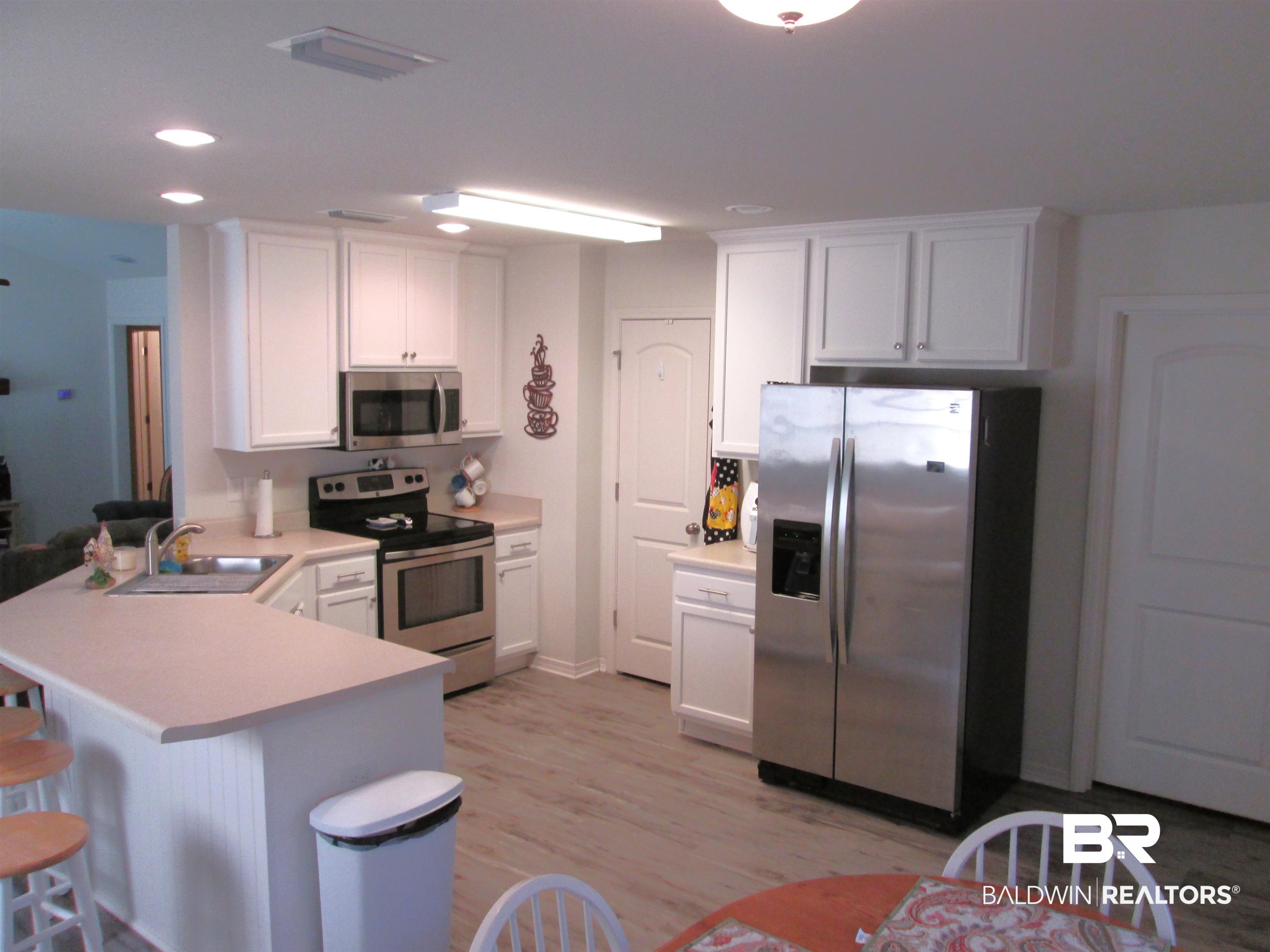 530 Brethren Church Road Fruitdale, AL 36539 - Photo 6 of 24 Kitchen with kitchen peninsula, appliances with stainless steel finishes, light hardwood / wood-style floors, a kitchen bar, and white cabinetry