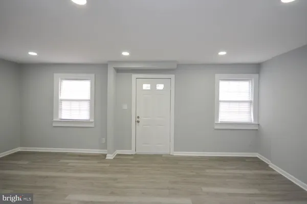 a view of an empty room with wooden floor and window