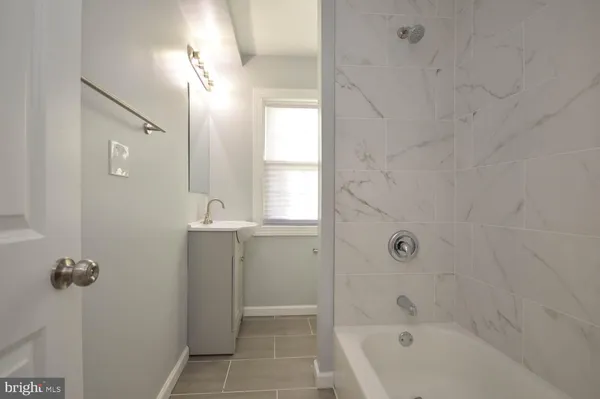 a bathroom with a bathtub a window a shower and vanity