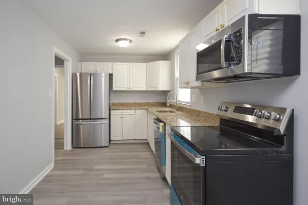 a kitchen with a sink a microwave a refrigerator and cabinets