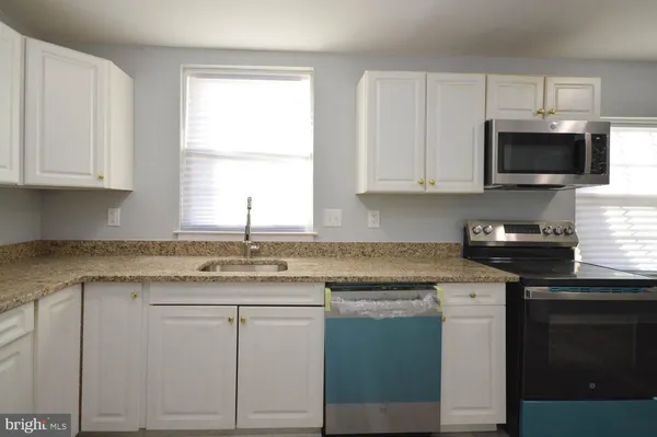 a kitchen with granite countertop white cabinets and a sink