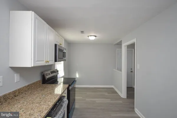 a kitchen with granite countertop a sink a stove and cabinets