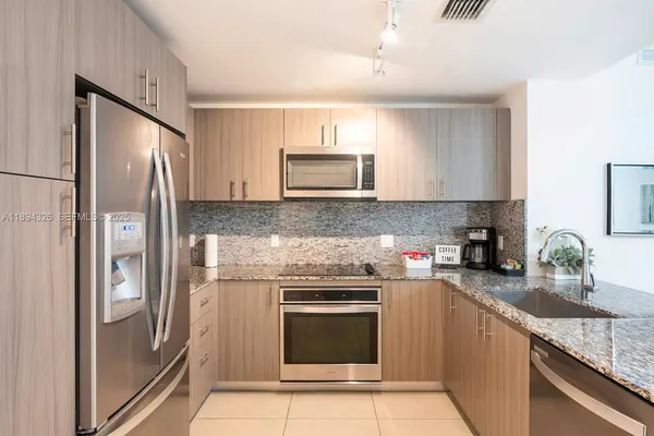 a kitchen with granite countertop a refrigerator stove and sink