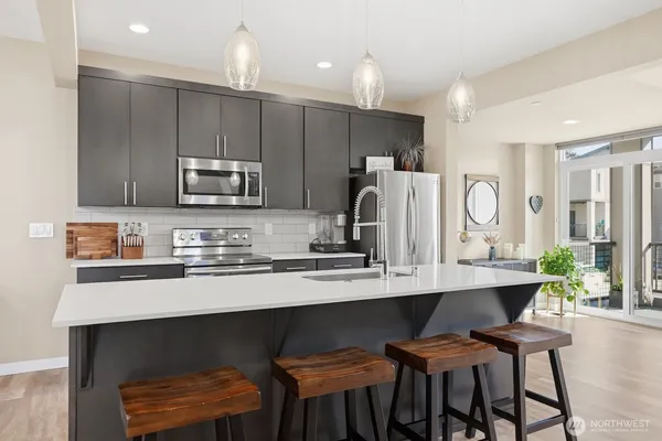 a kitchen with stainless steel appliances kitchen island granite countertop a table chairs in it and wooden floors