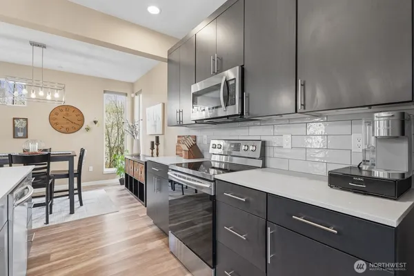 a kitchen with stainless steel appliances granite countertop a sink wooden cabinets and wooden floor