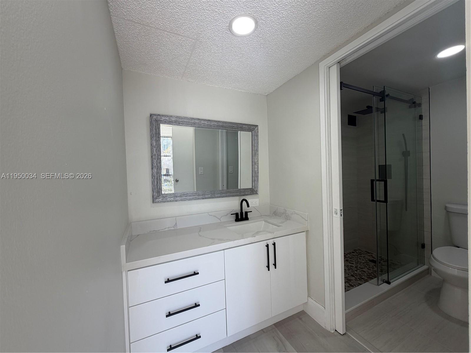 17021 North Bay Road, Unit 216 Sunny Isles Beach, FL 33160 - Photo 21 of 40 a bathroom with a granite countertop sink mirror and toilet