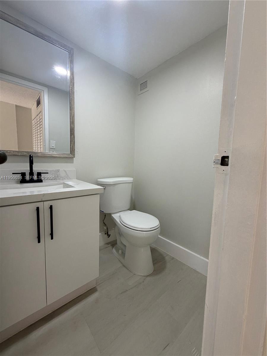 17021 North Bay Road, Unit 216 Sunny Isles Beach, FL 33160 - Photo 9 of 40 a bathroom with a toilet sink vanity and mirror