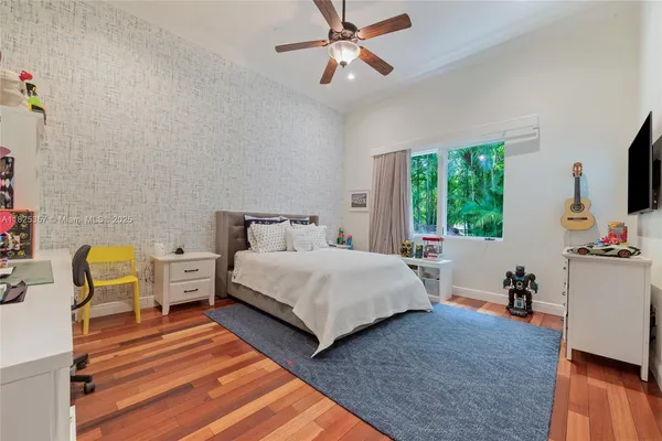 a bedroom with a bed a couch and a flat tv screen on dresser