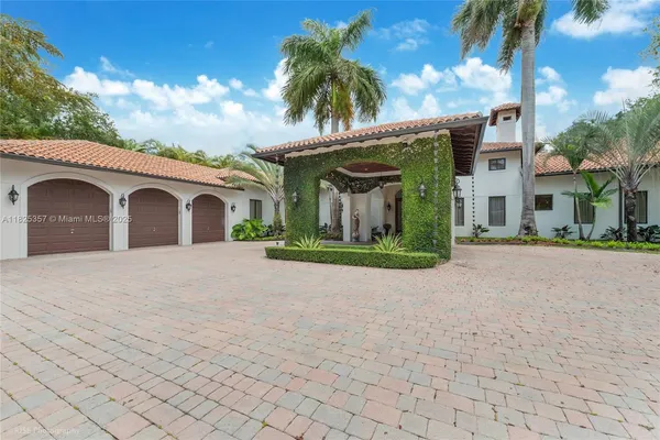 a view of a white house with a yard and palm trees