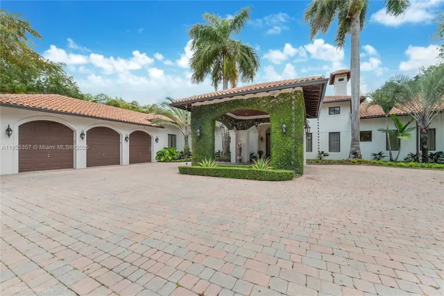 a view of a white house with a yard and palm trees