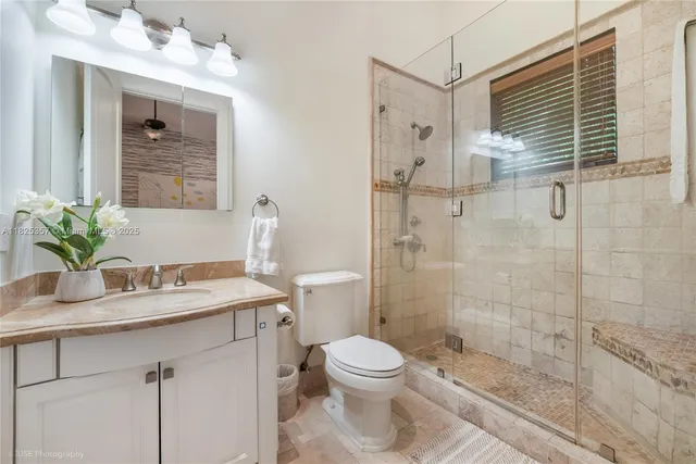 a bathroom with a granite countertop sink a toilet and shower