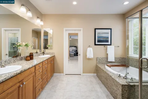 a spacious bathroom with a granite countertop sink a mirror a bathtub and shower