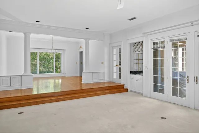 an empty room with windows a fireplace and a chandelier fan
