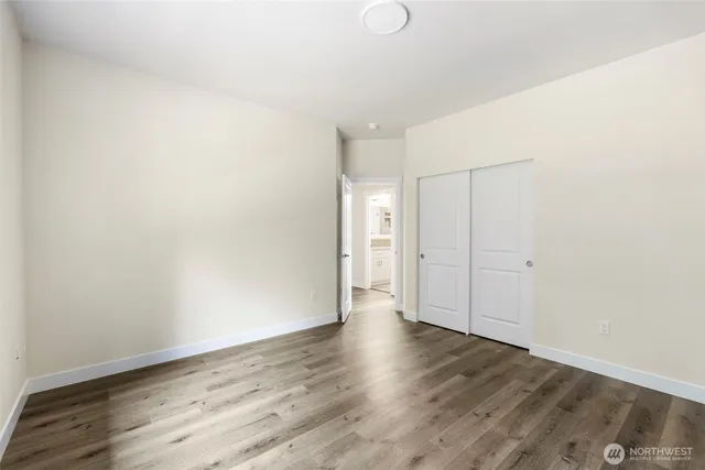 a view of an empty room with wooden floor and closet