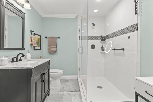 a bathroom with a granite countertop sink a mirror a shower and a toilet