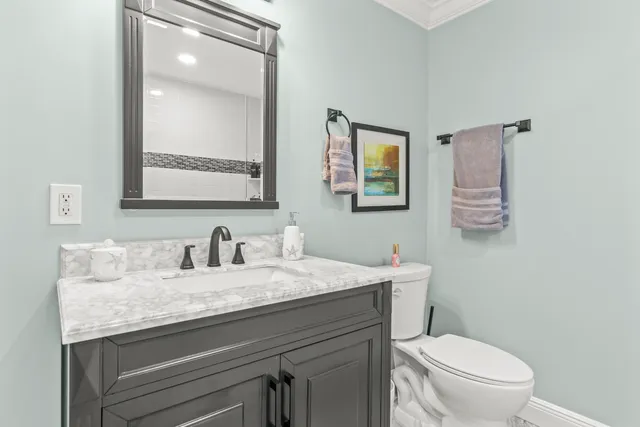a bathroom with a granite countertop toilet sink and mirror