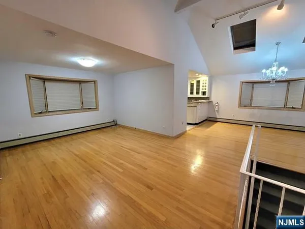 a view of an empty room with window and wooden floor