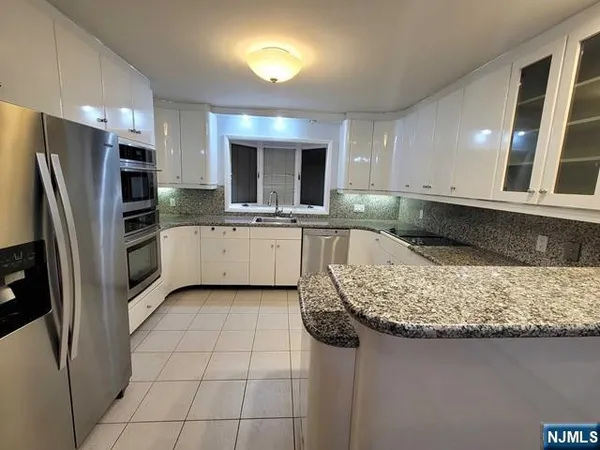 a kitchen with stainless steel appliances granite countertop a sink refrigerator and microwave