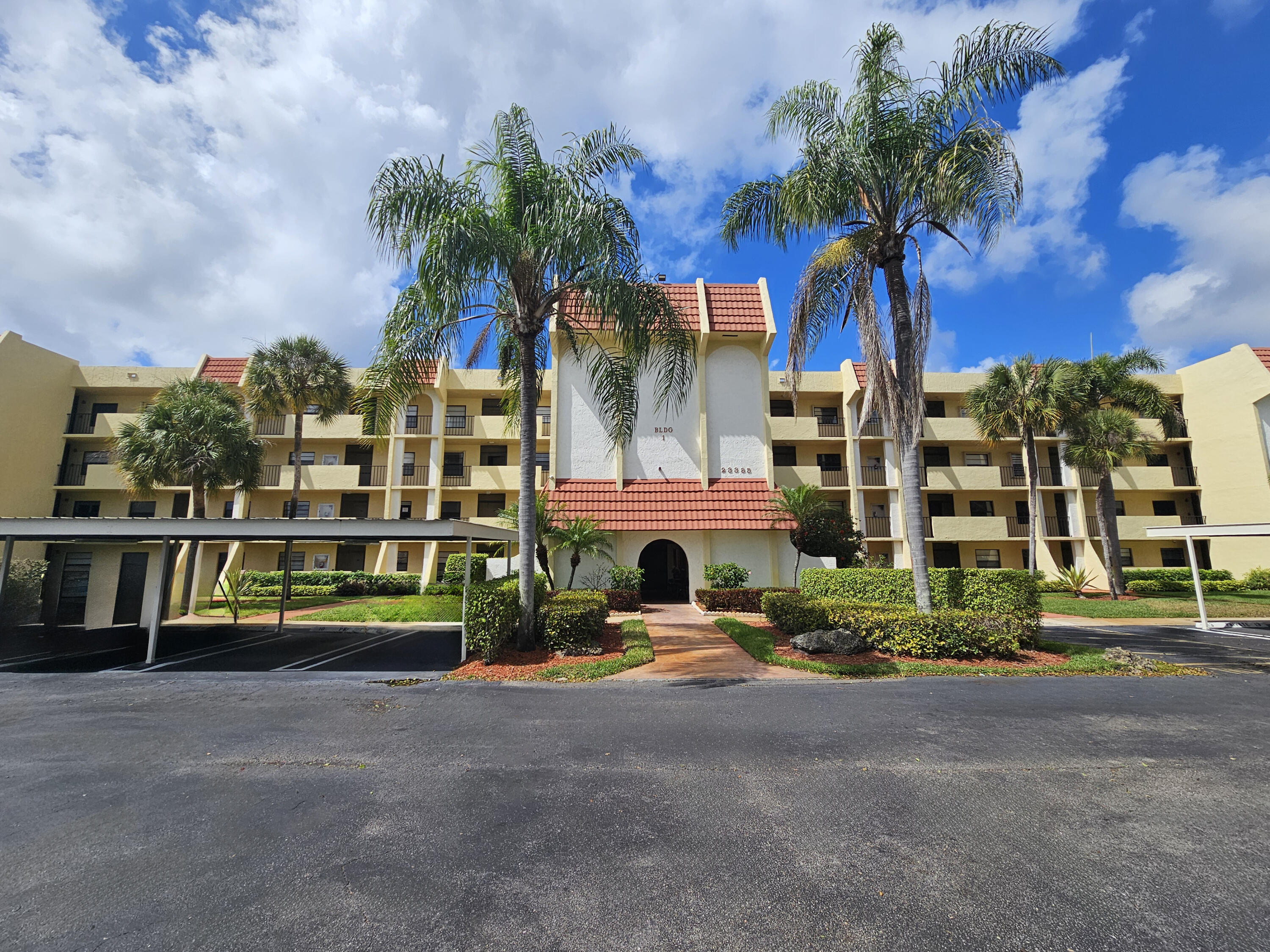 23385 South Barwood Lane, Unit 1203 Boca Raton, FL 33428 - Photo 2 of 22 a front view of a house with a garden and trees