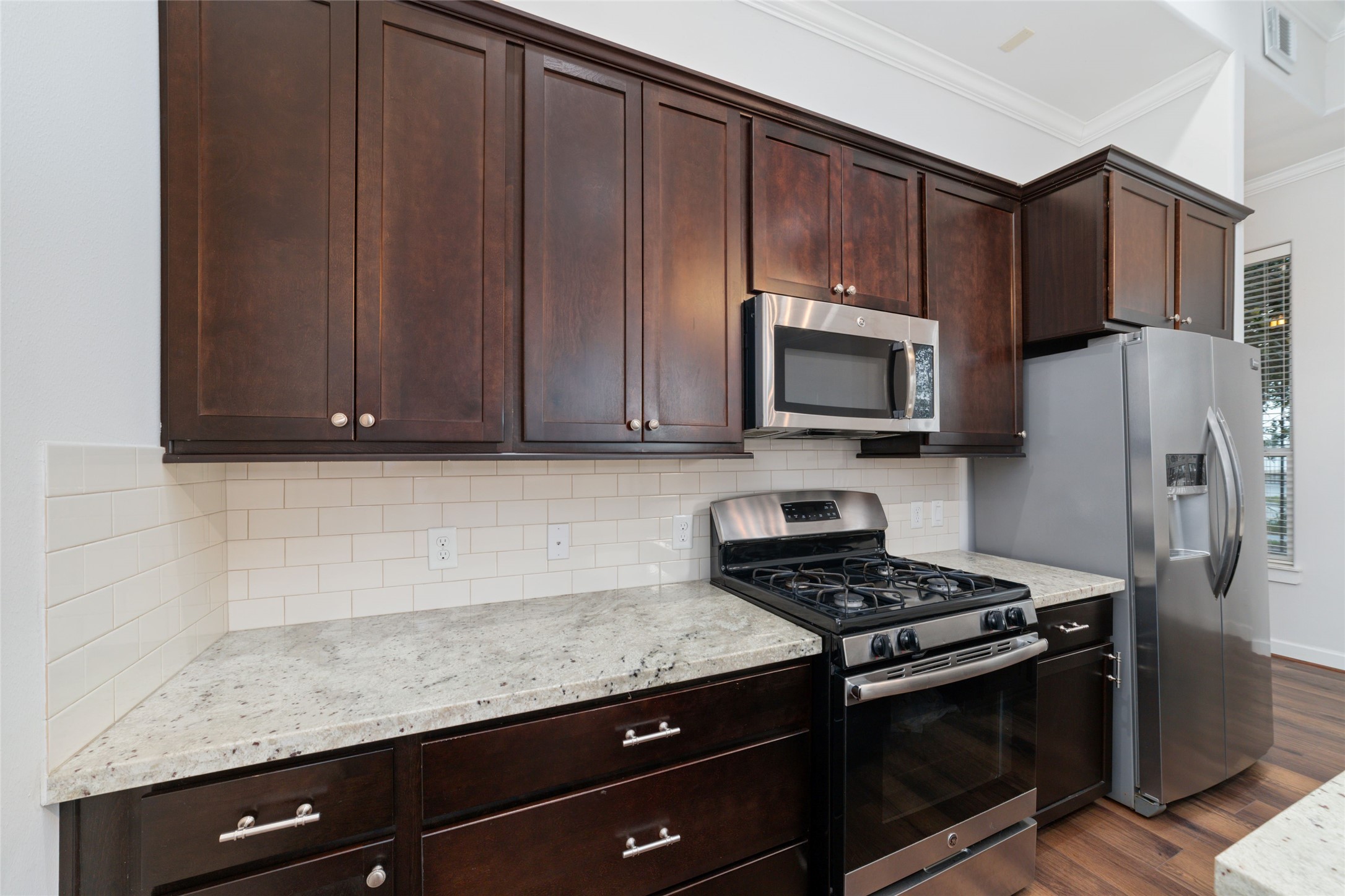 902 West 20th Street, Unit A Houston, TX 77008 - Photo 4 of 23 a kitchen with granite countertop wooden cabinets and stainless steel appliances