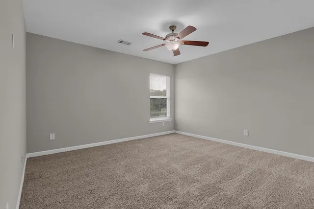 a view of an empty room with chandelier fan