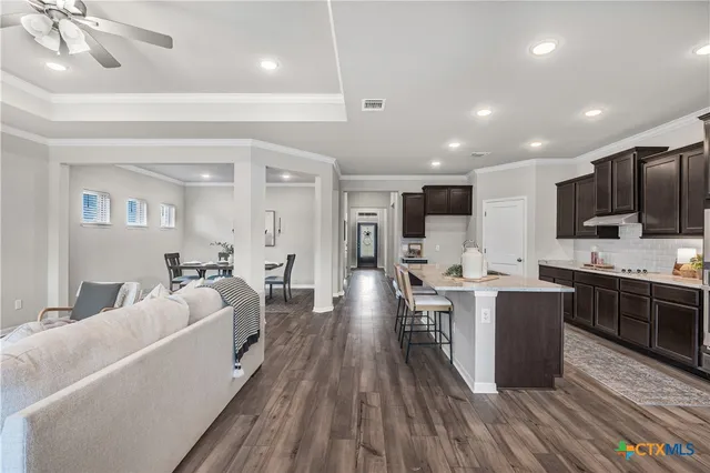 a large living room with stainless steel appliances granite countertop a couch and chandelier